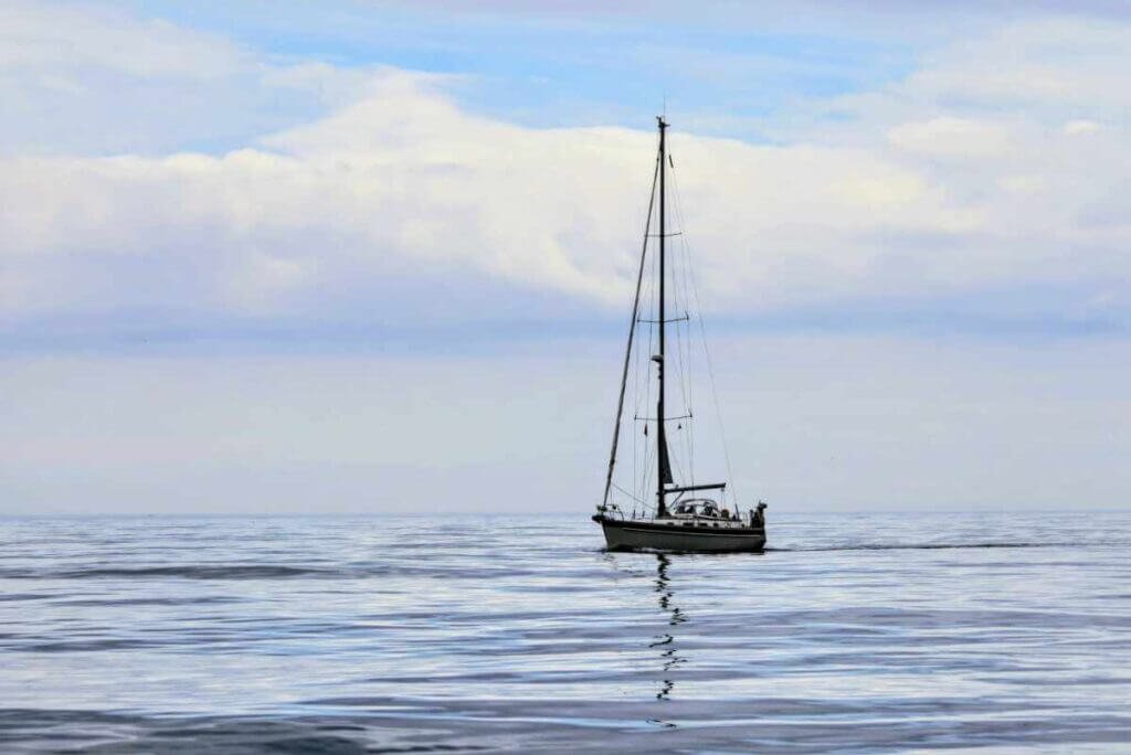 A sailing boat on calm North Sea waters viewed from Lindisfarne Castle on the Pilgrims Way to Holy Island