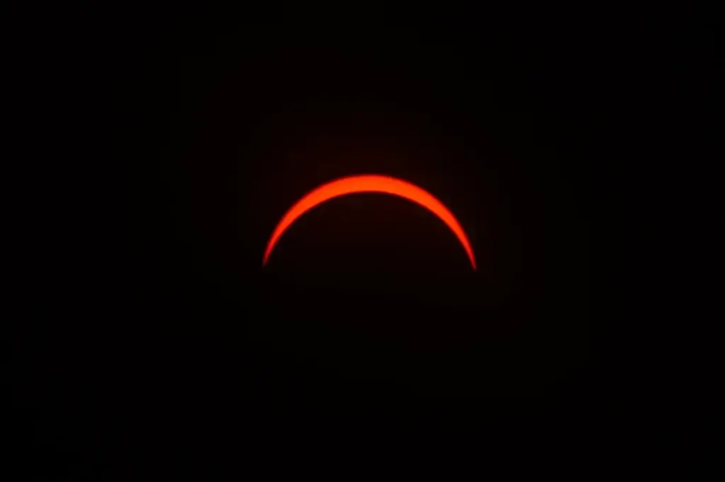 A tight close-up shot capturing the bright orange red crescent sun at peak totality when chasing the eclipse.