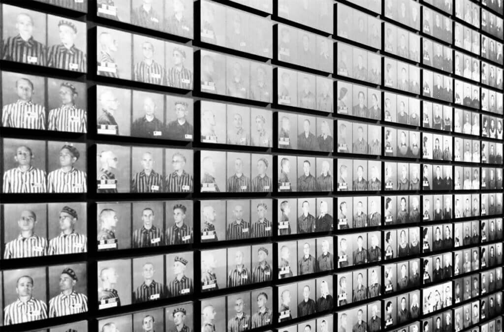 Black and white photograph of the wall of prisoner registration identification portraits at Auschwitz.