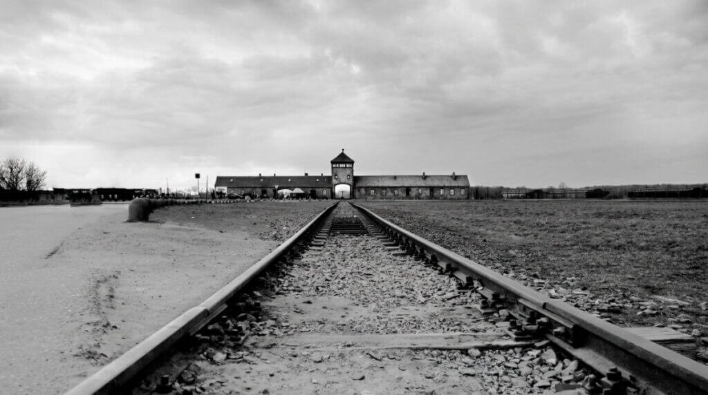 Krakow and Auschwitz trip. Black and white photograph of train tracks leading to the main entrance gatehouse at Auschwitz-Birkenau.