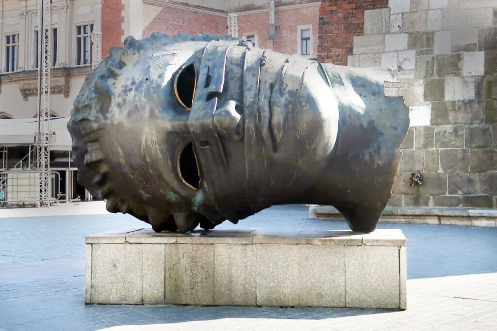 The famous "Eros Bendato" bronze sculpture of a giant, hollowed-out human head lying on its side in Kraków’s Main Market Square.