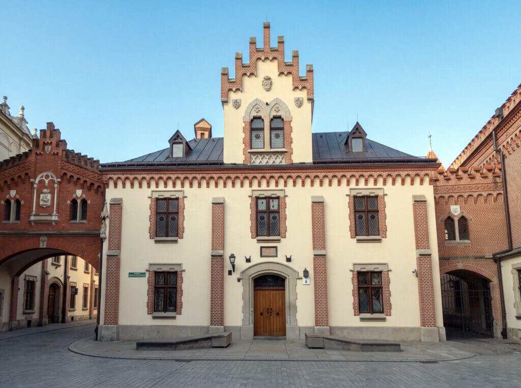 Front view of the historic cream-colored Czartoryski Museum building in Kraków with distinct red brick trim and a decorative stepped gable rooftop.