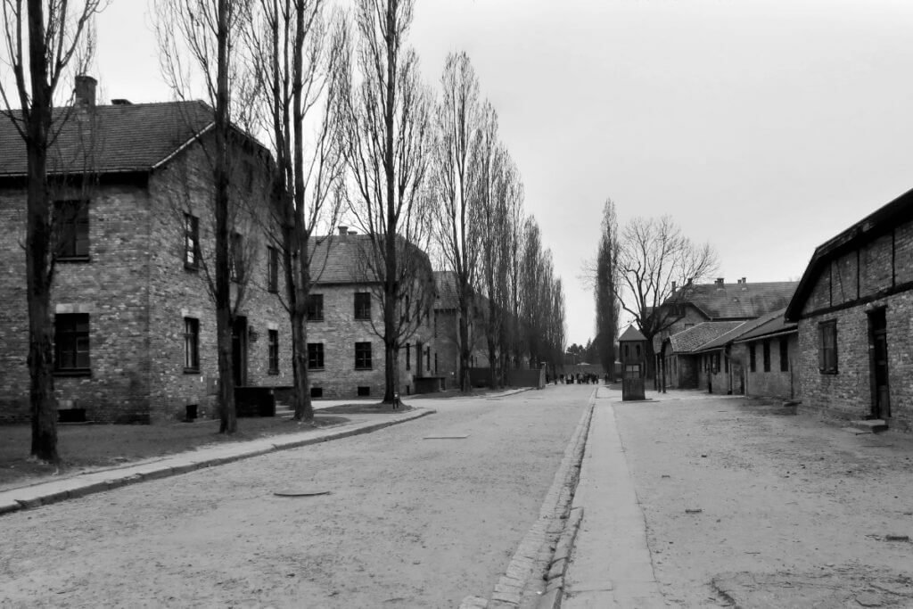Black and white photograph of brick prisoner barracks and tree-lined avenues at Auschwitz I.