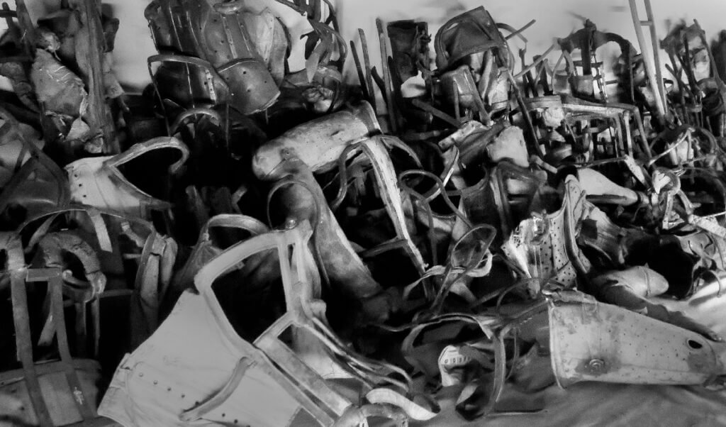 Black and white photograph of confiscated prosthetic limbs and orthopedic braces at Auschwitz.